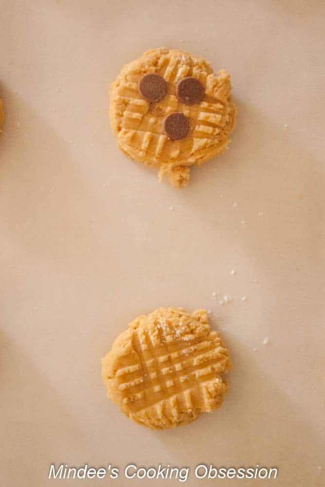 Peanut Butter Cookie dough scooped out, flattened with a fork and topped with chocolate chips.