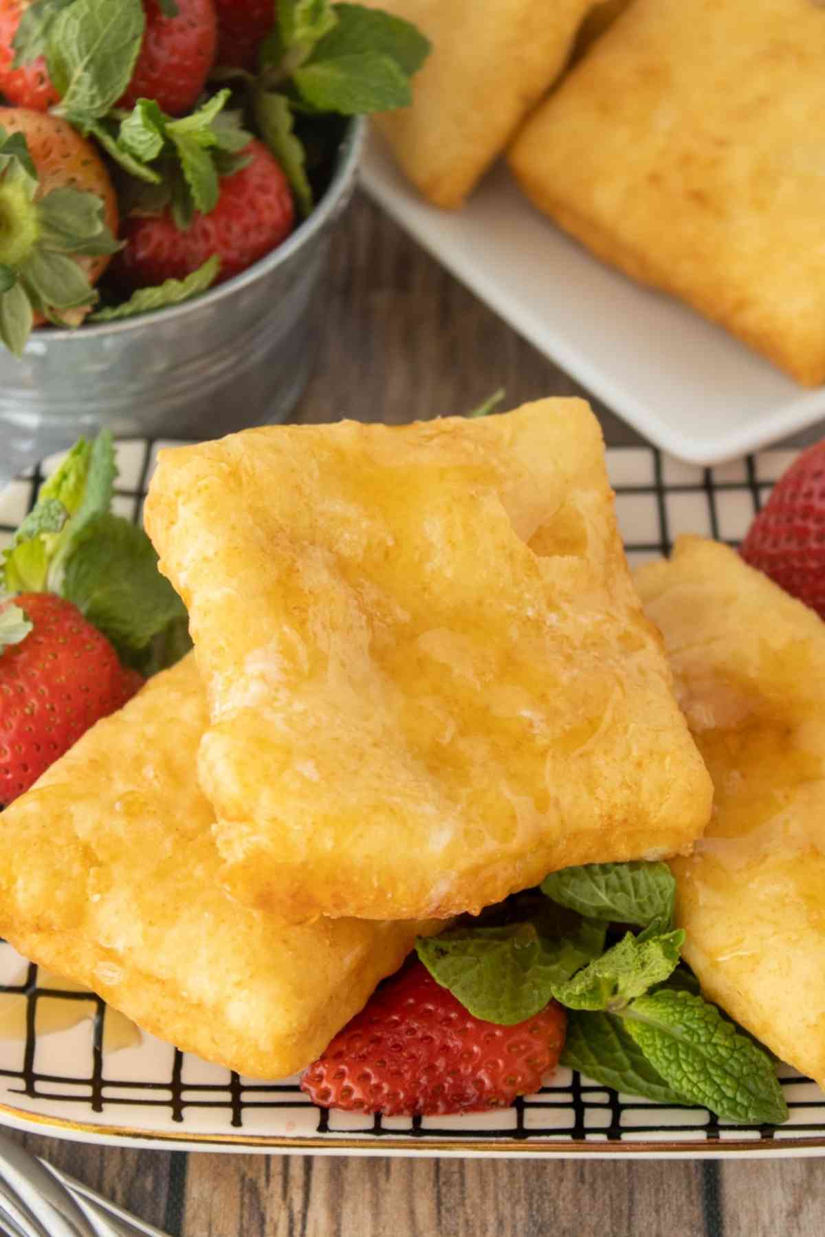 Fried scones on a plate with fresh strawberries.