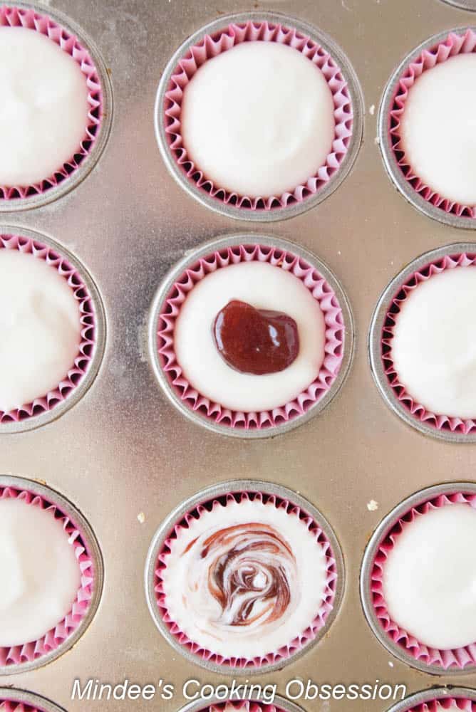 Raspberry Swirl Cheesecake Bites filling added over the crust and a dot of jam swirled in the center.