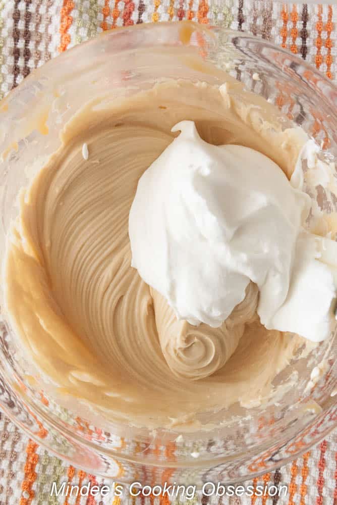 One third of the whipped cream being folded into the caramel cream cheese mixture.
