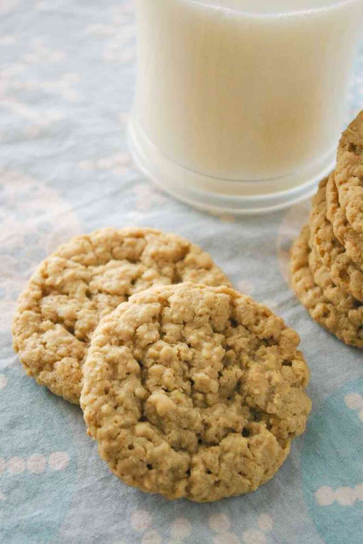 A  stack of oatmeal cookies by a tall glass of milk.