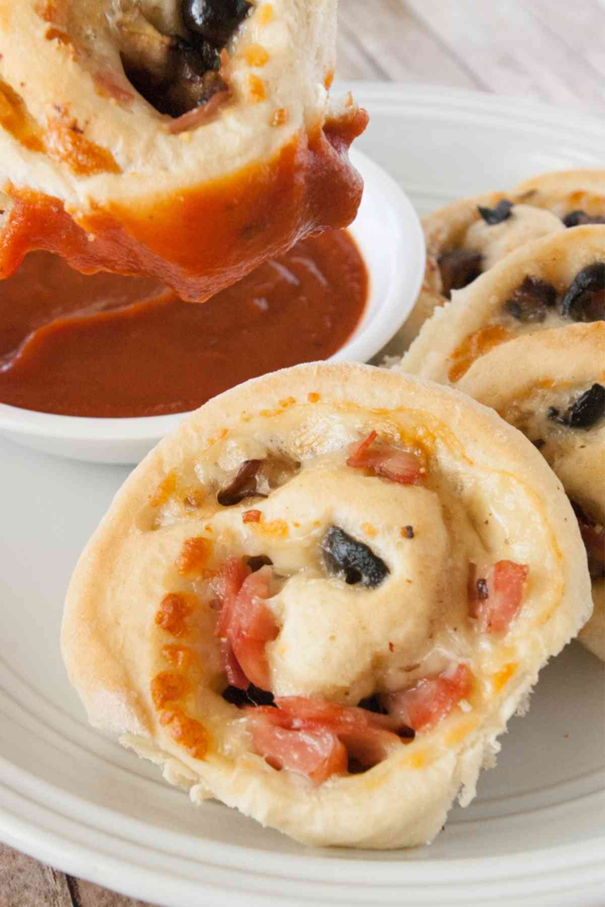 A pizza roll being dipped in pizza sauce.