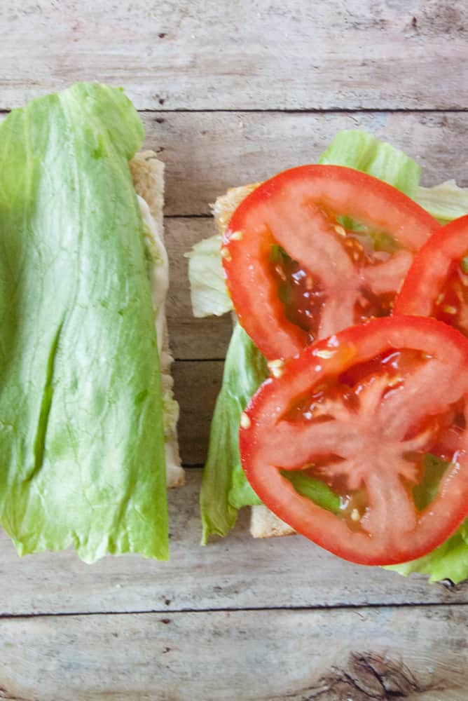 Mayo guac spread halves topped with lettuce and tomato slices.