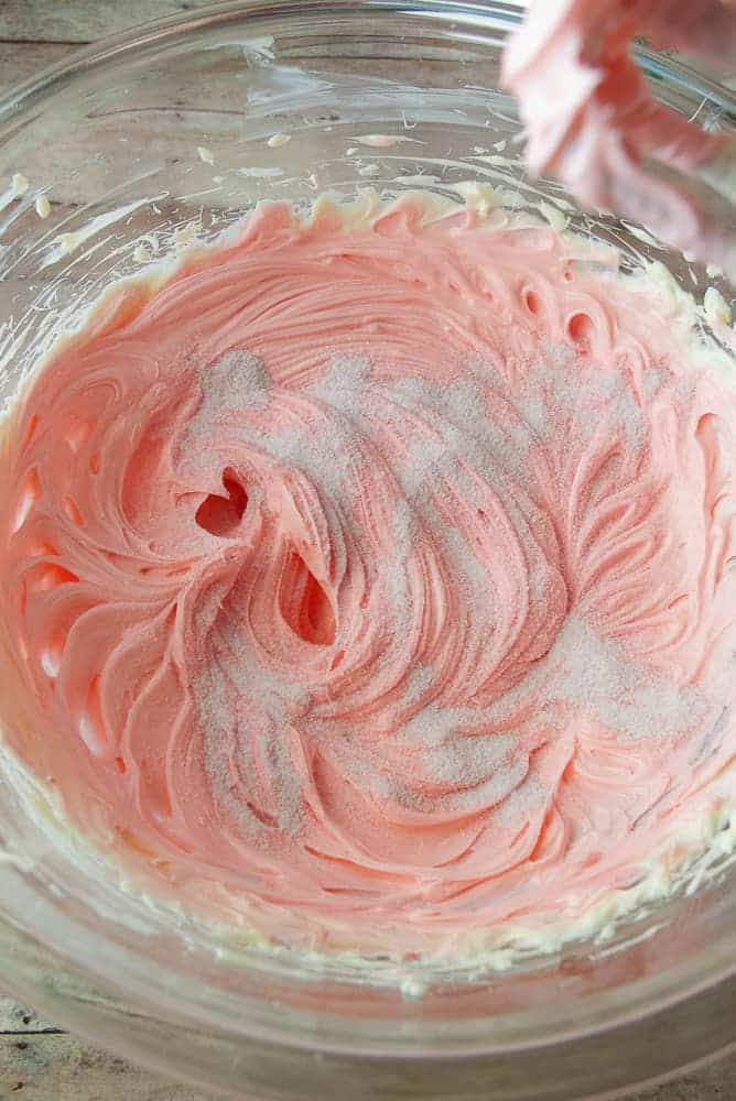 Butter, shortening, salt, and pink food coloring beat together with raspberry lemonade mix sprinkled on the top.