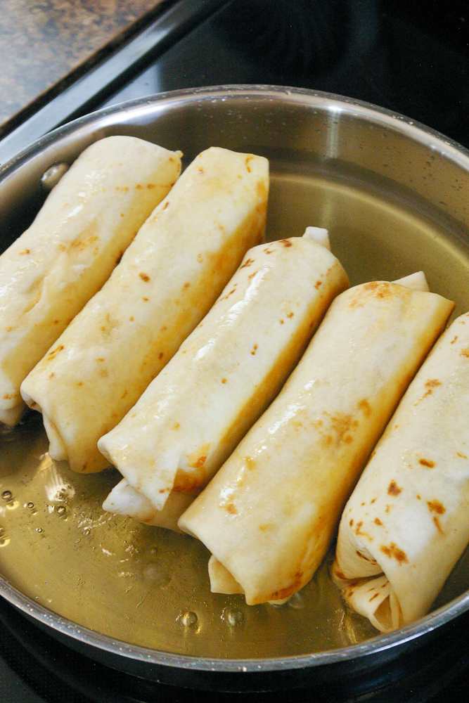 Chicken chimichangas frying in oil.