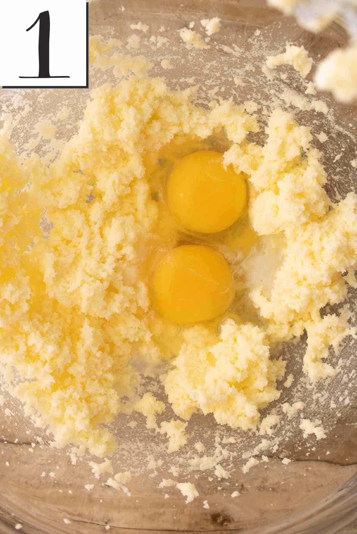 Eggs cracked into the bowl with creamed butter and sugar.