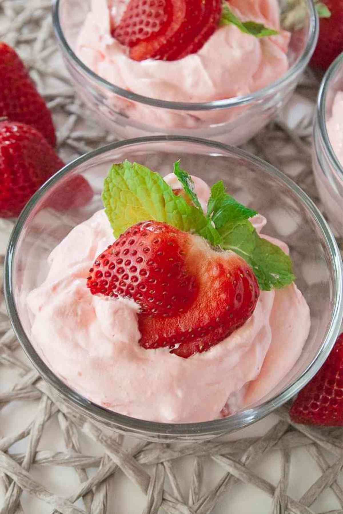 Little bowls of berries and cream jello salad garnished with fresh strawberries.
