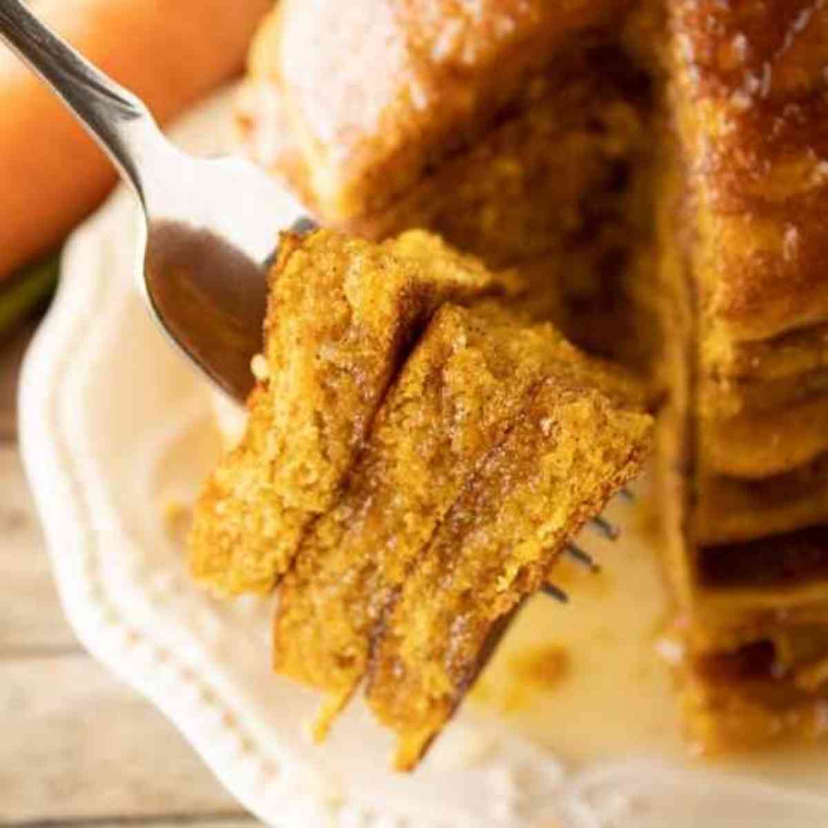 A fork lifting a bite of carrot cake pancakes.