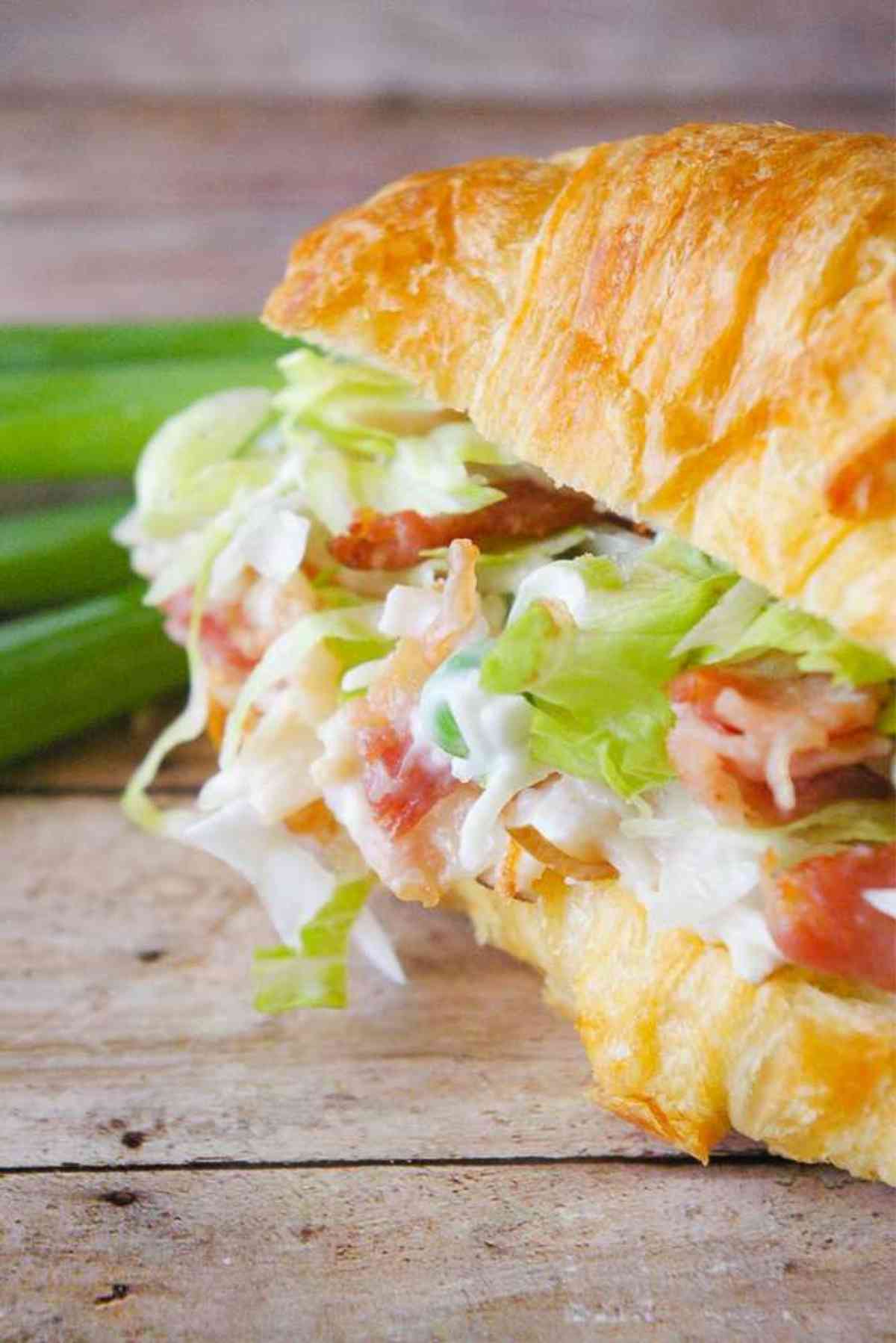 Turkey Salad Croissant next to some green onions.