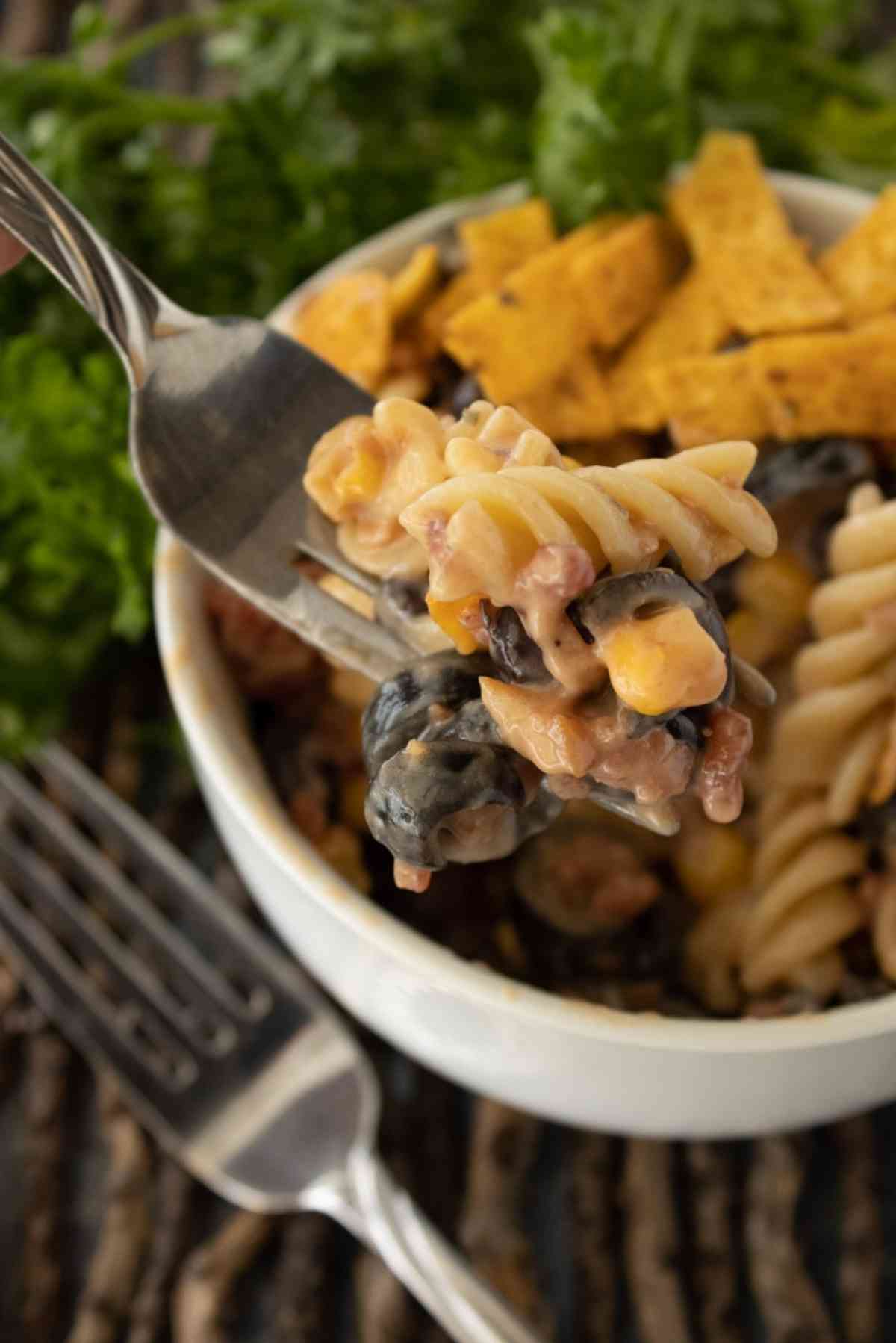 Fork lifting a bite of barbecue ranch pasta salad out of a bowl.