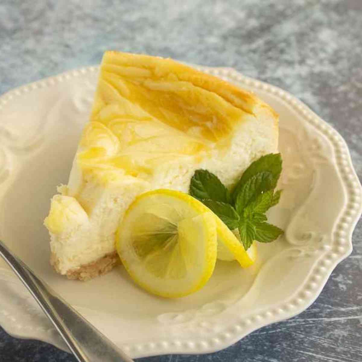 Slice of lemon swirl cheesecake garnished with mint
