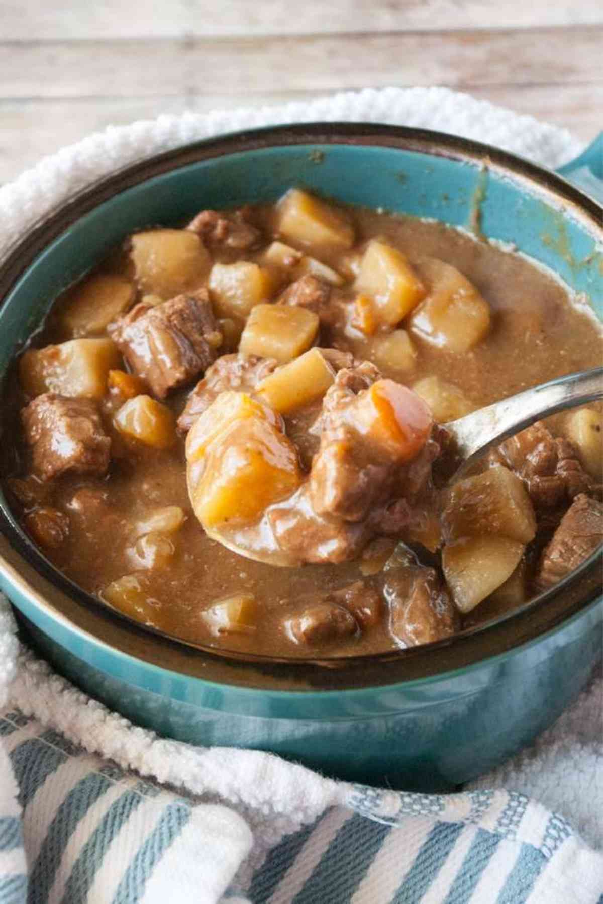 A spoonful of tender beef and root  vegetables in a flavorful beef stew.