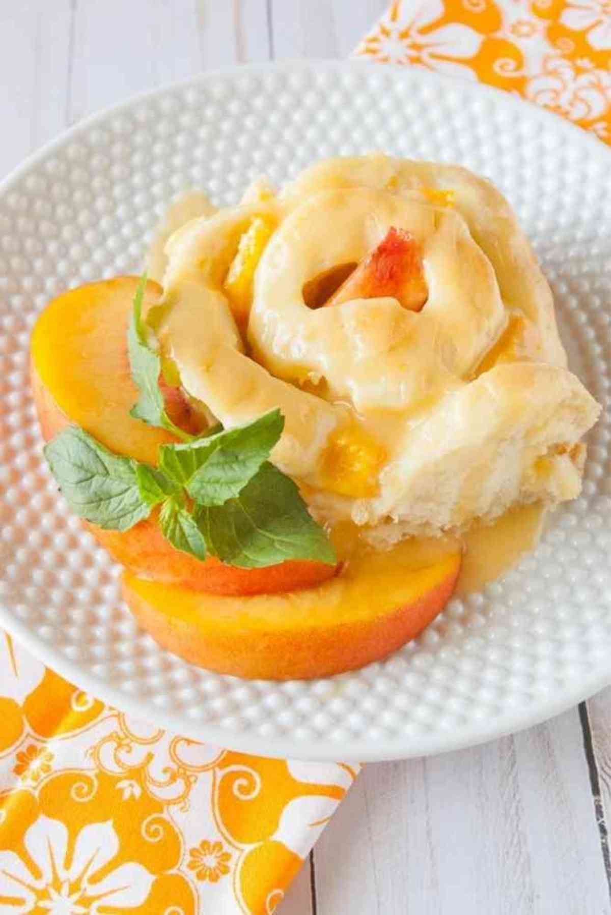 A Peaches and Cream Sweet Roll garnished with fresh peaches and mint!