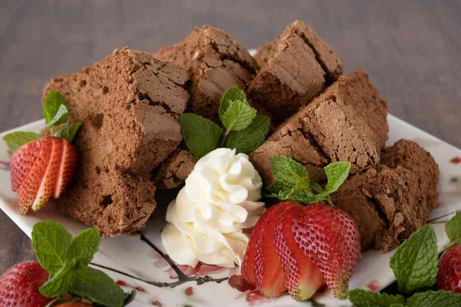 Wedges of chocolate angel food cake garnished with whipped cream and fresh strawberries.