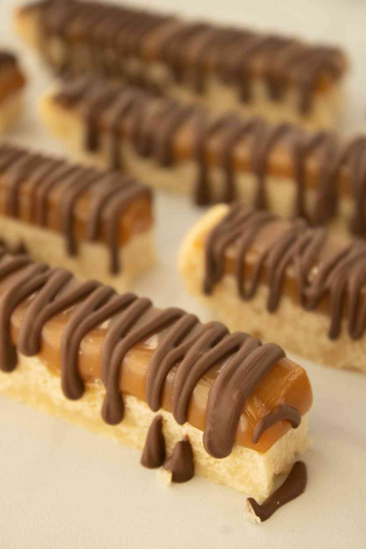 Twix cookie bars lined up and drizzled with chocolate.