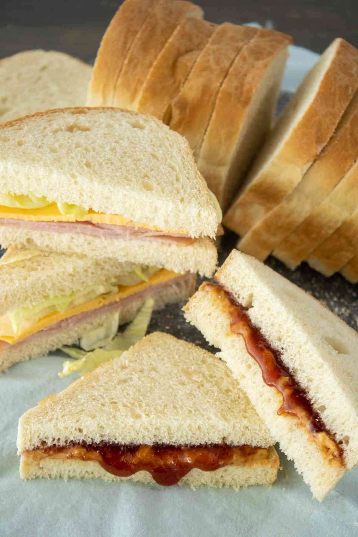 Sliced loaf of bread next to a ham sandwich.