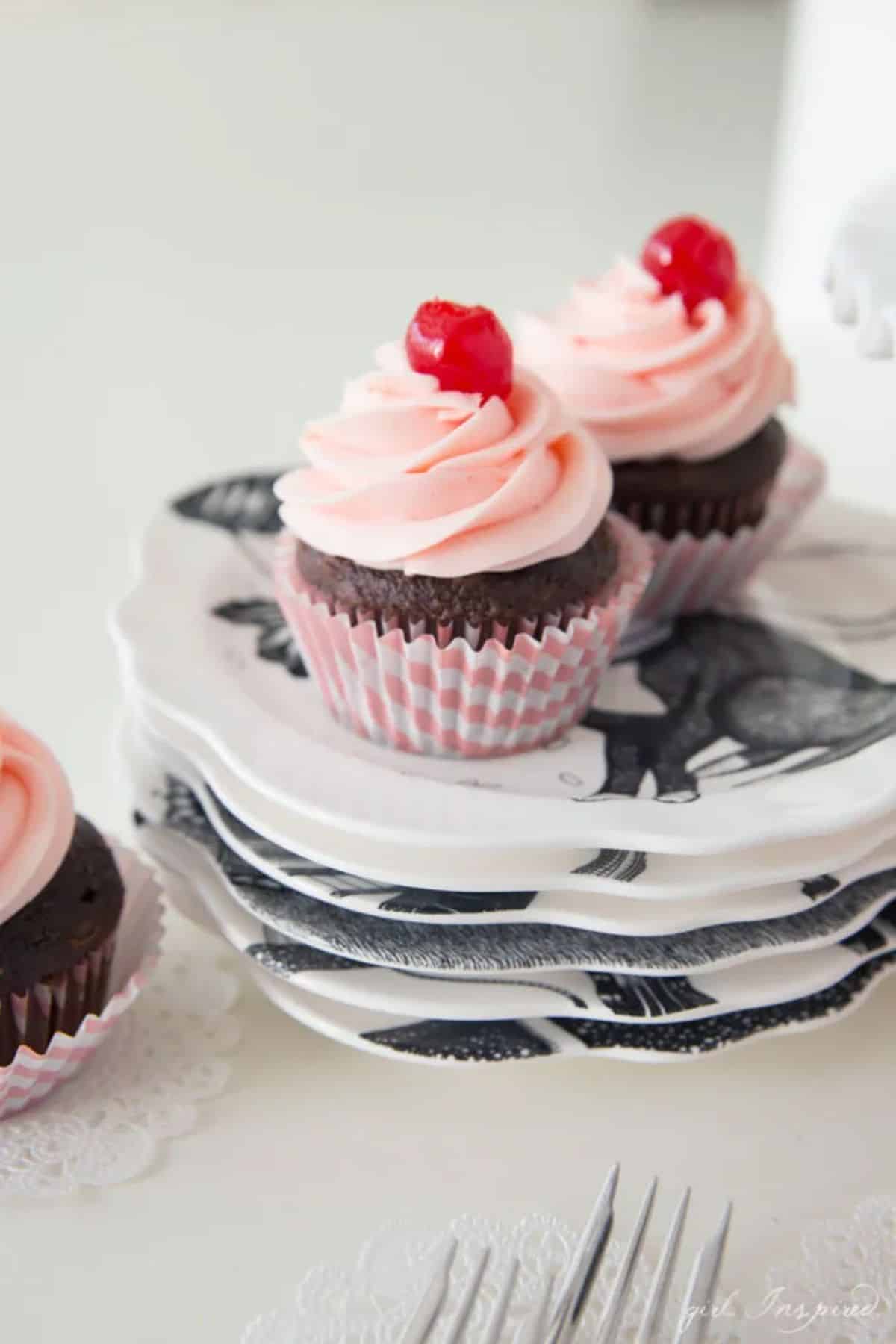 Two cupcakes with Cherry Buttercream Frosting on a plate.