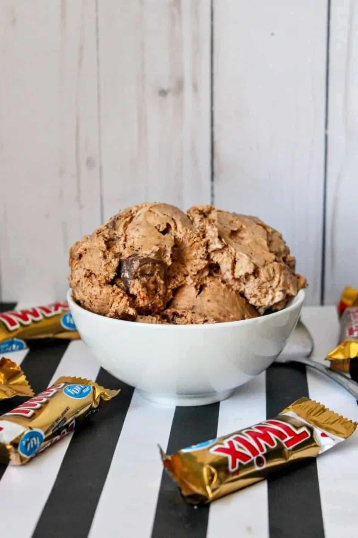 Twix Ice Cream in a white bowl with twix bars scattered around.