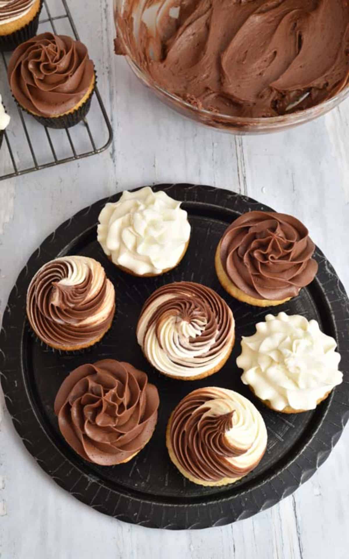 A bunch of cupcakes with Chocolate Ganache Cream Cheese Frosting on a black tray.