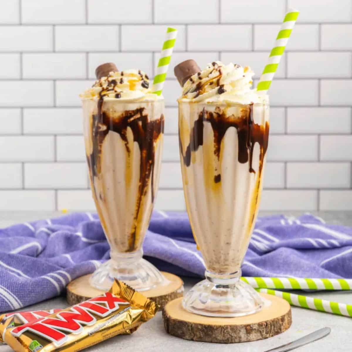Two Twix Milkshake in tall glasses with straws.