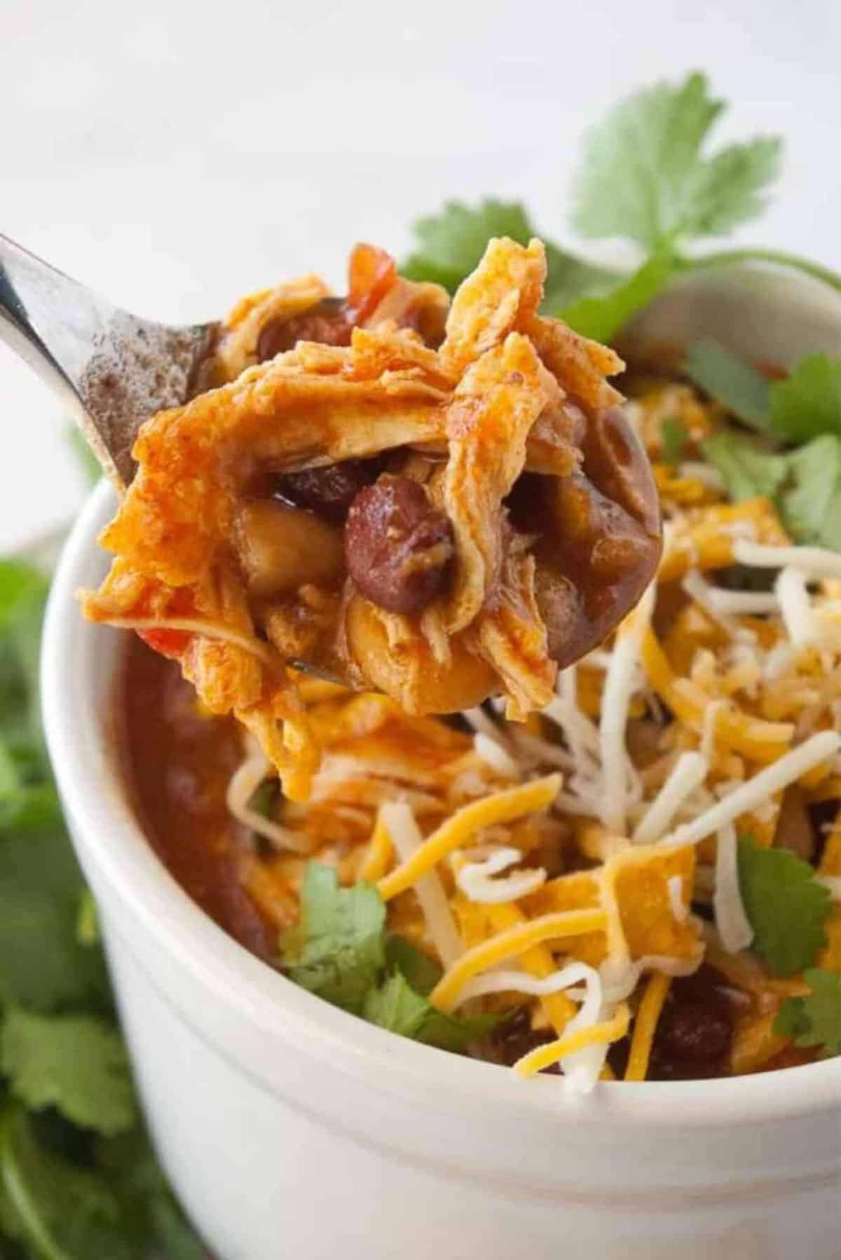 Instant Pot Chicken Chili in a white bowl picked with a spoon.