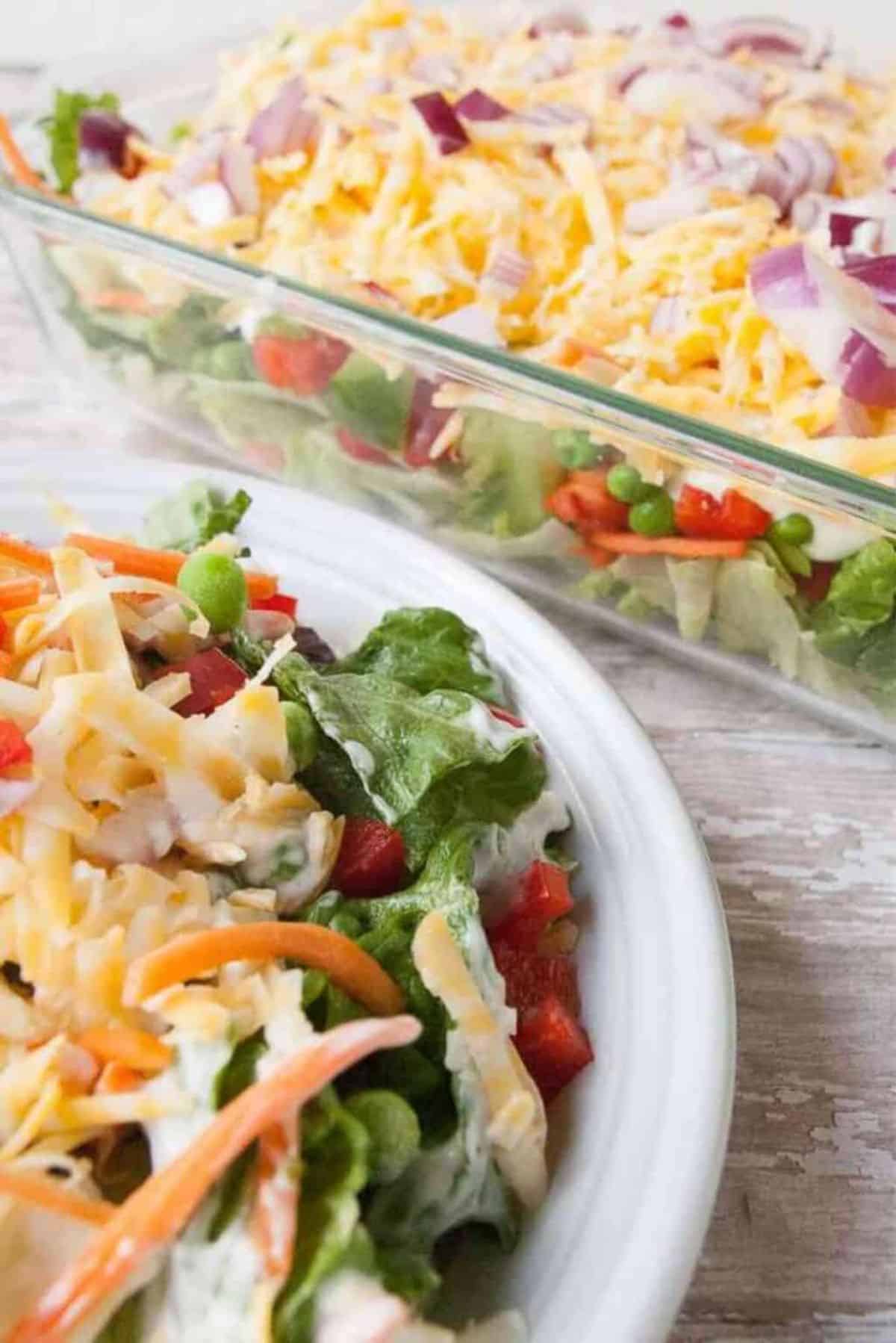 Healthy Overnight Layered Green Salad in a glass bowl and on a white plate.