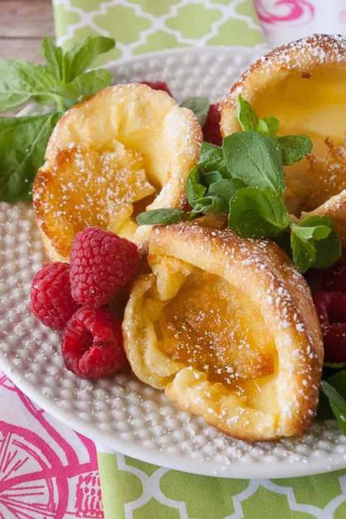 Mini German Pancakes with raspberries on a whte tray.