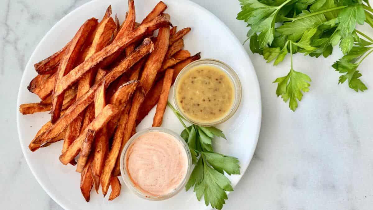 Deep Fried Sweet Potato Fries with dips in bowls on a white plate.