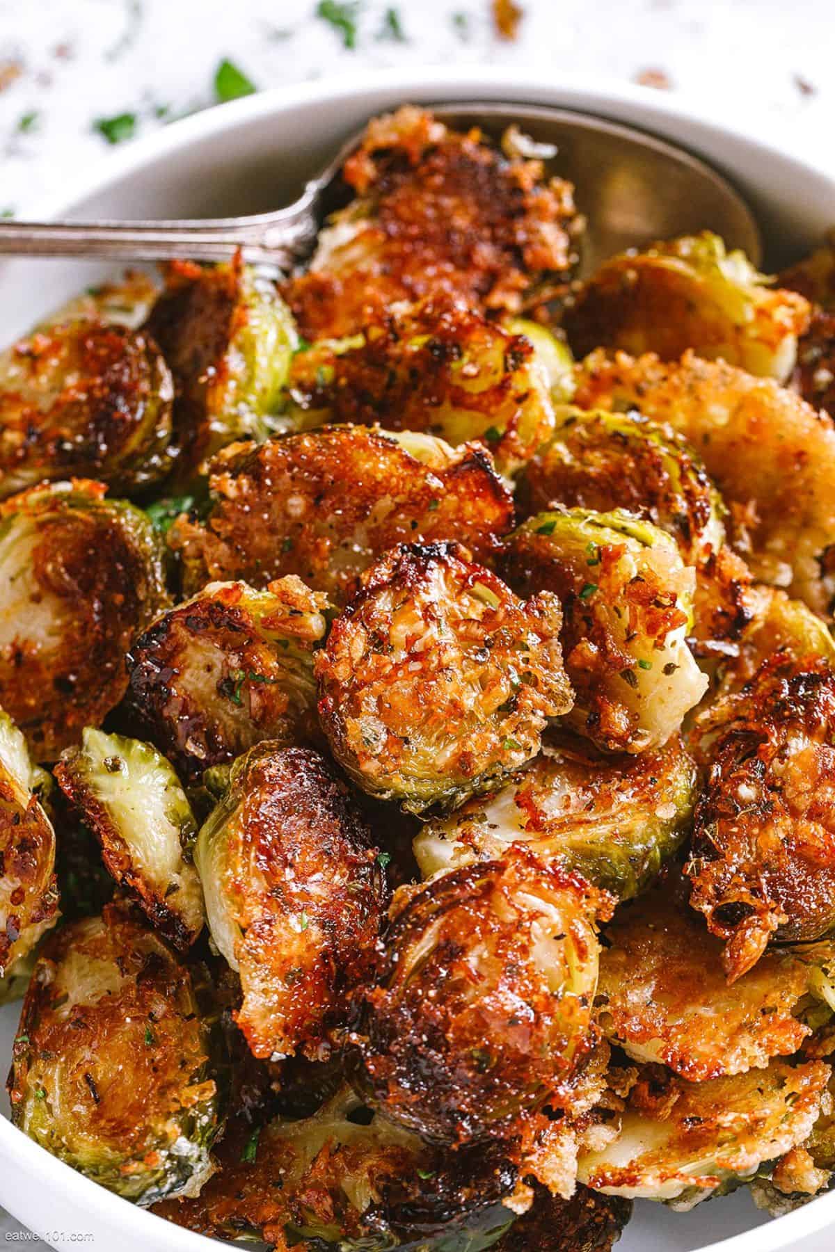 Delicious Garlic Parmesan Roasted Brussels Sprouts in a white bowl with a spoon.