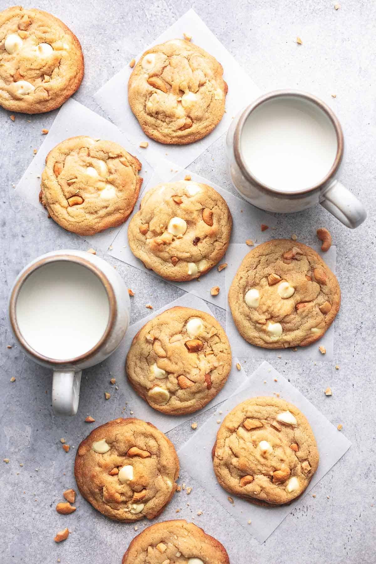 Chewy White Chocolate Cashew Cookies with two cups of milk on a table.
