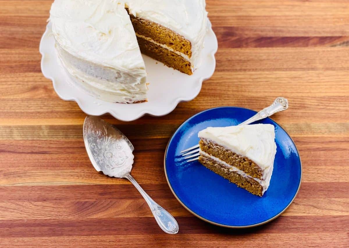 Sweet Potato Spice Cake on a cake tray and a piece of cake on a smal blue plate.