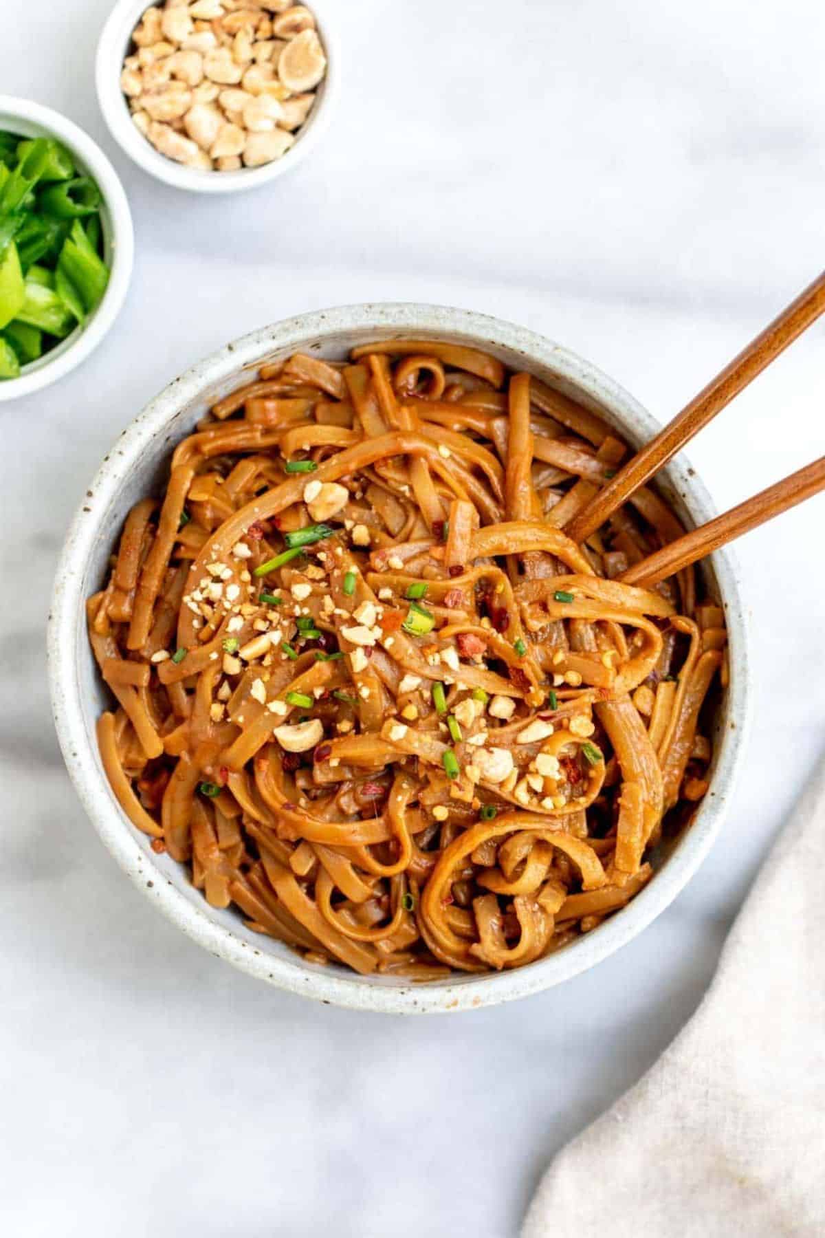 15 Minute Spicy Peanut Butter Noodles in a white bowl with chopsticks.