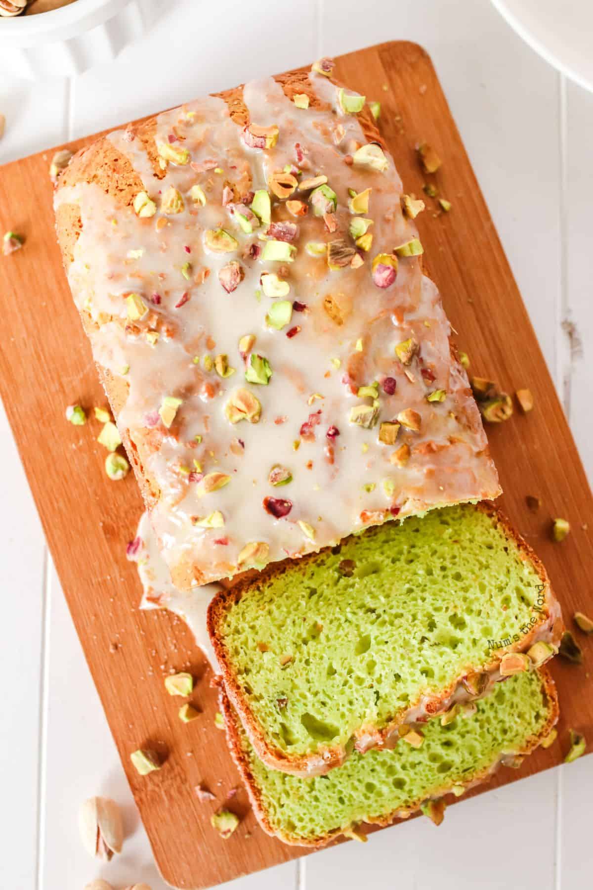 Partialy sliced Pistachio Bread on a wooden cutting board.