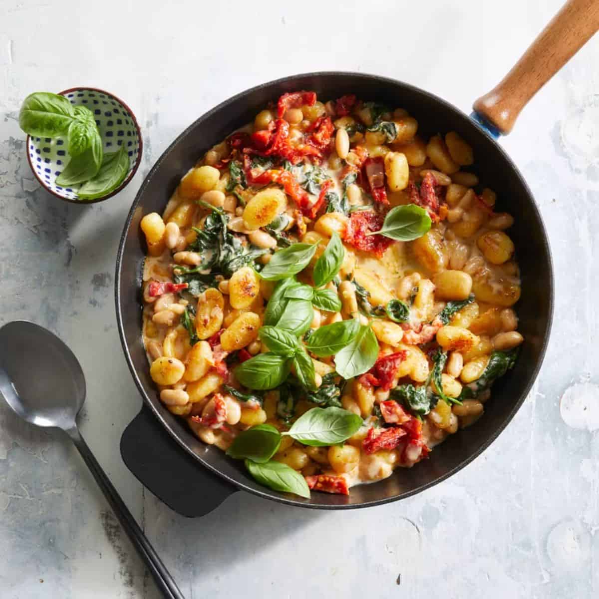 White Bean& Sun-dried Tomato Gnocchi in a black skillet.