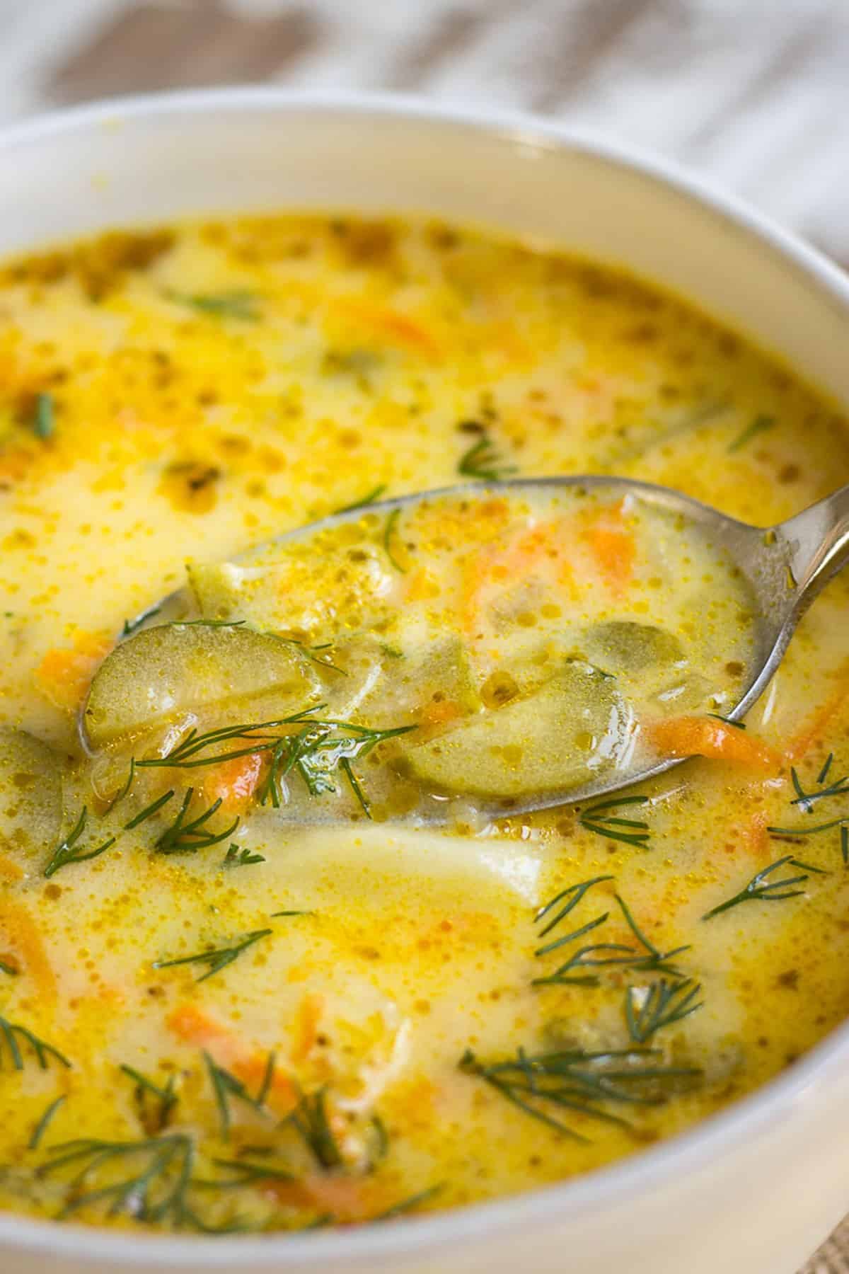 Dill Pickle Soup in a white bowl with a spoon.