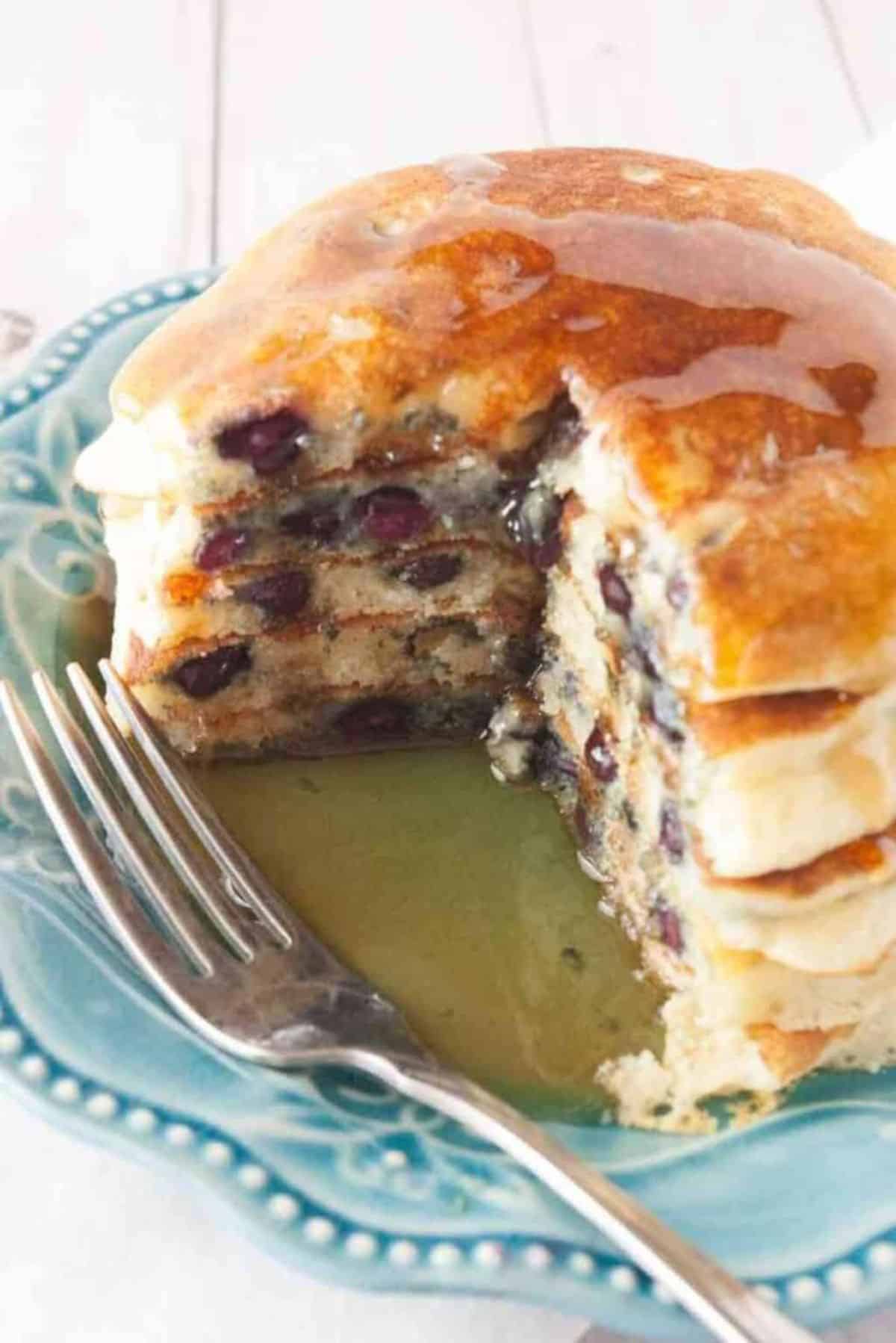 A pile of delicious Wild Blueberry Buttermilk Pancakes on a blue plate with a fork.