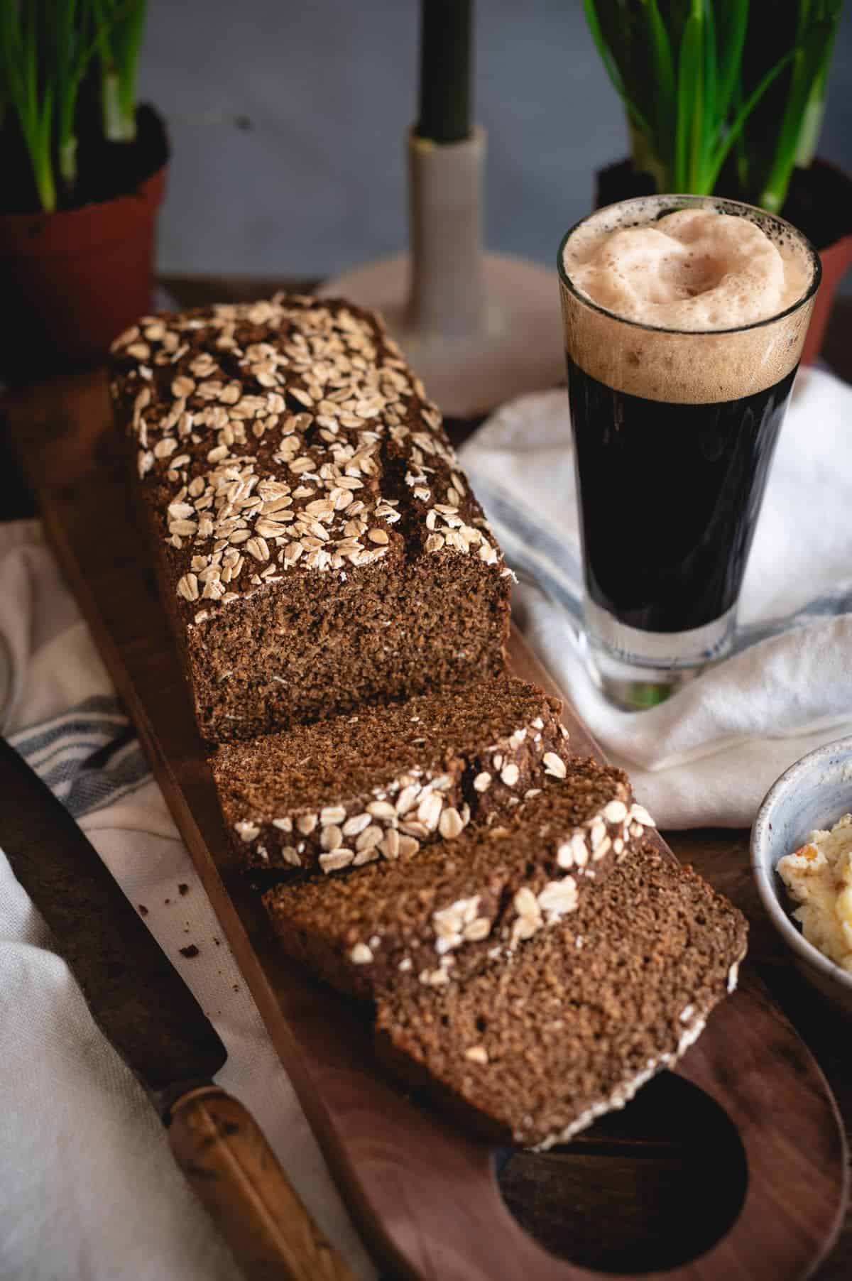 Partially sliced Guinness Bread on a wooden cutting board.
