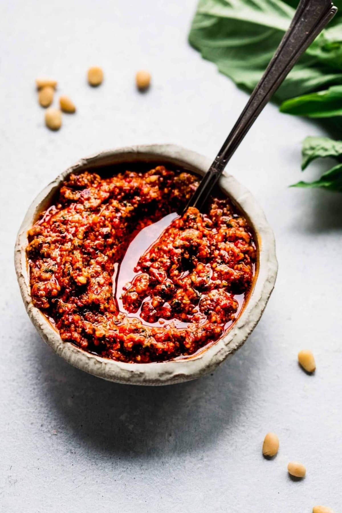 Sun-dried Tomato Pesto in a small bowl with a a spoon.