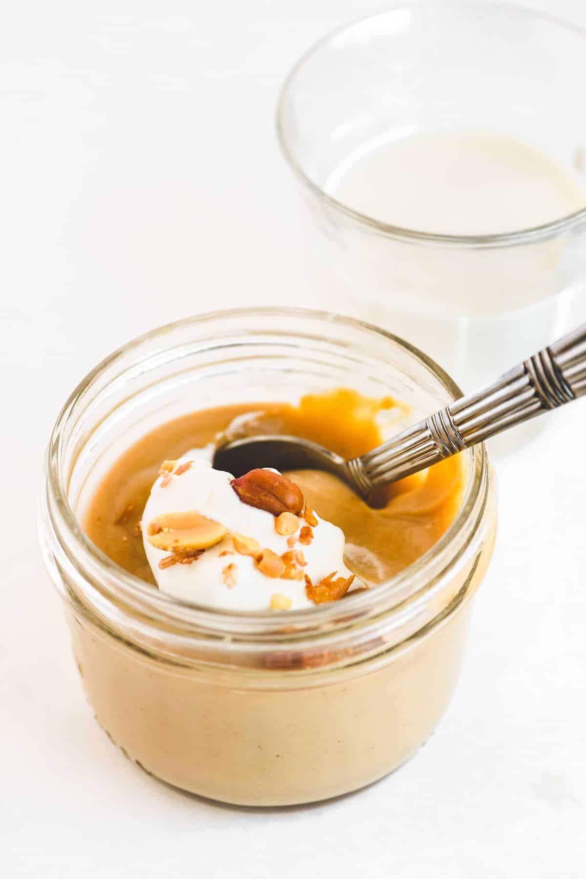 Heavenly Peanut Butter Pudding in a glass jar with a spoon.