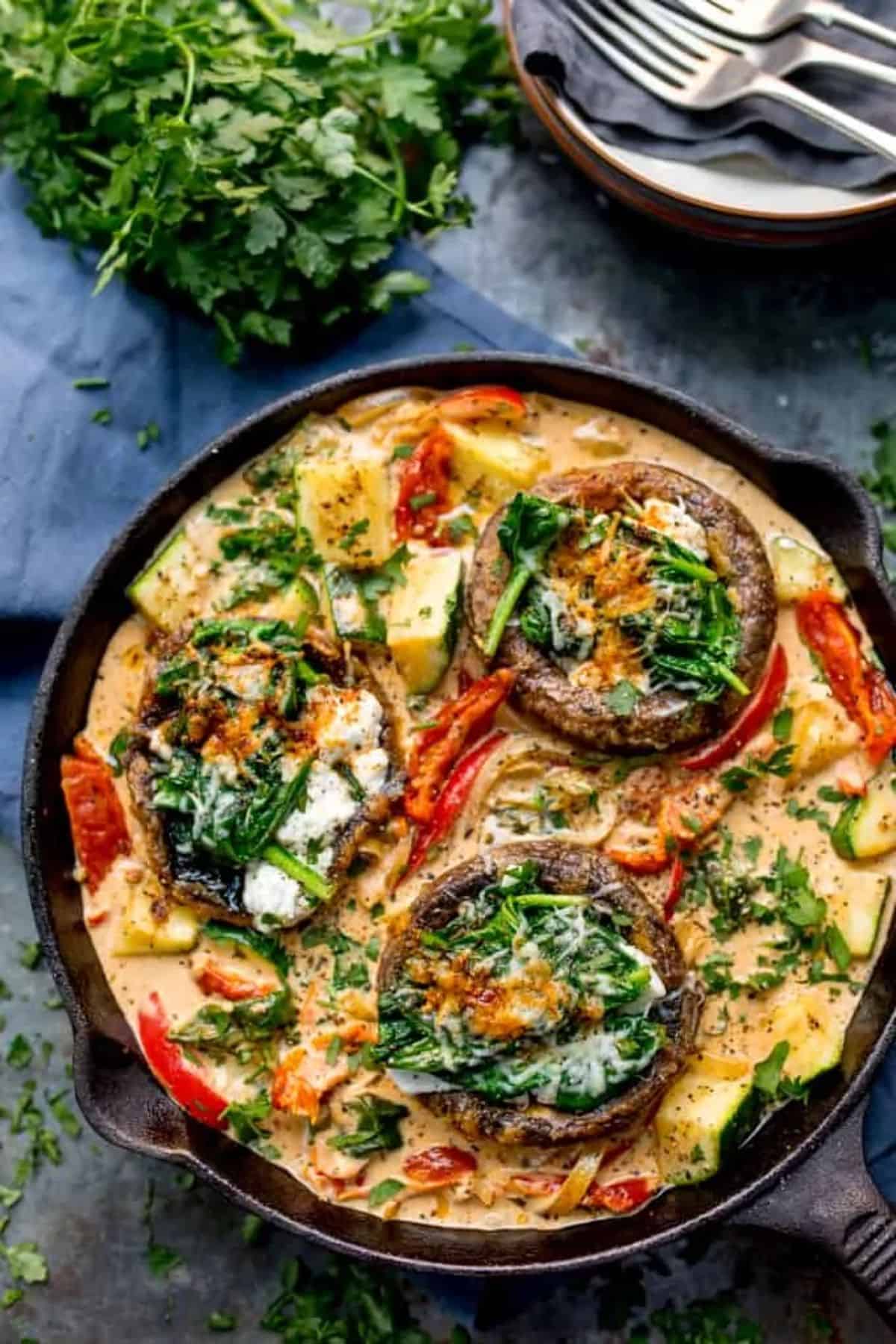 Tuscan Style Stuff Mushrooms in Creamy Sun-dried Tomato Sauce in a black skillet.