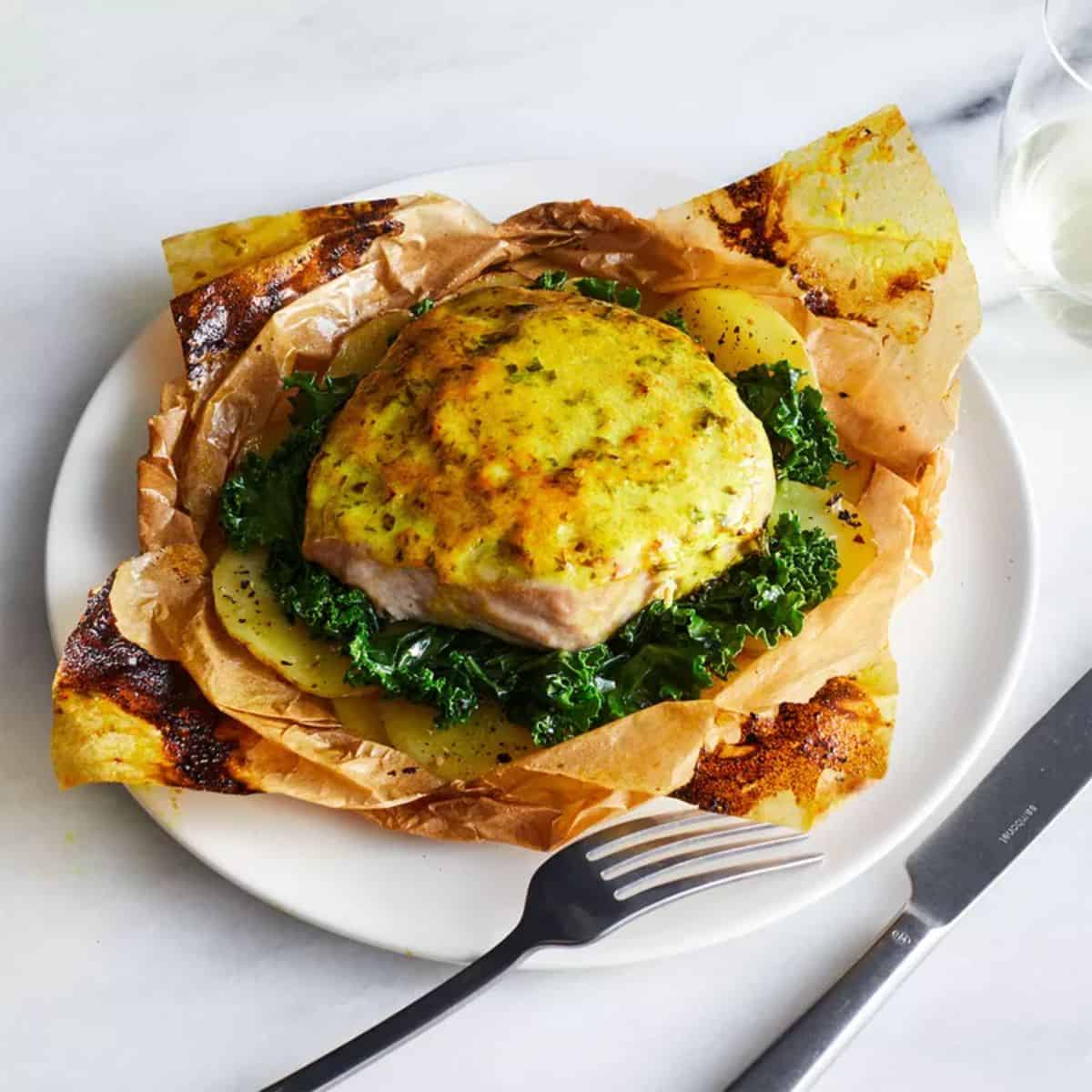 Tuna Steaks With Turmeric Sauce on a white plate with cutlery.