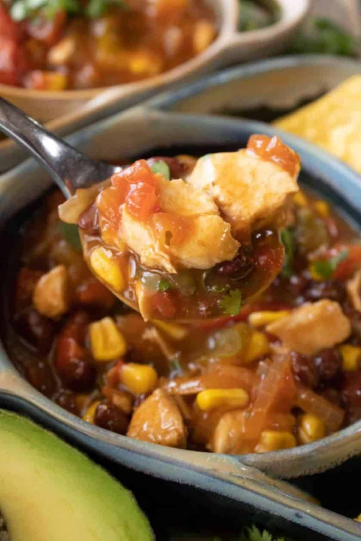 Crockpot Chicken Fajita Soup in a gray bowl picked with a spoon.