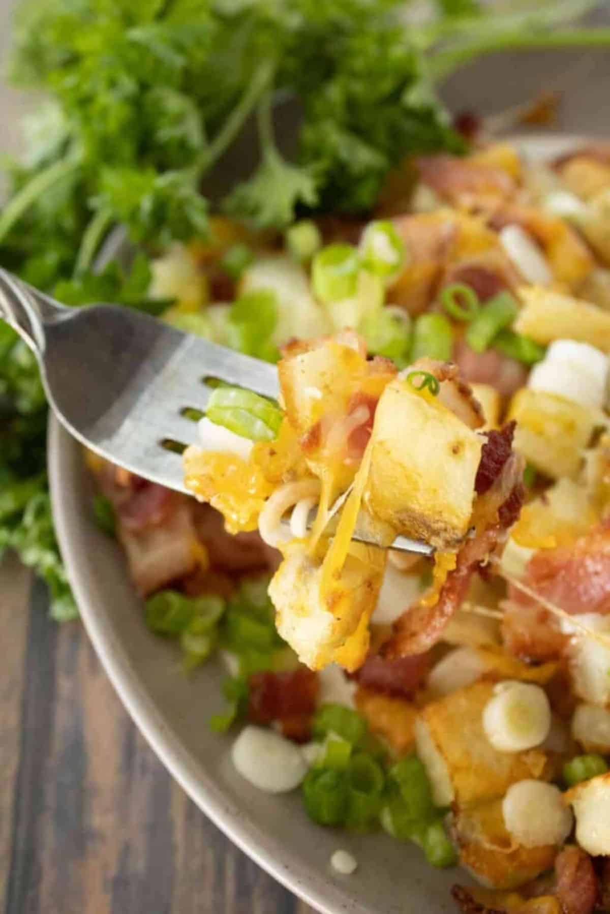 Tasty Roasted Loaded Potatoes on a fork and on a gray plate.