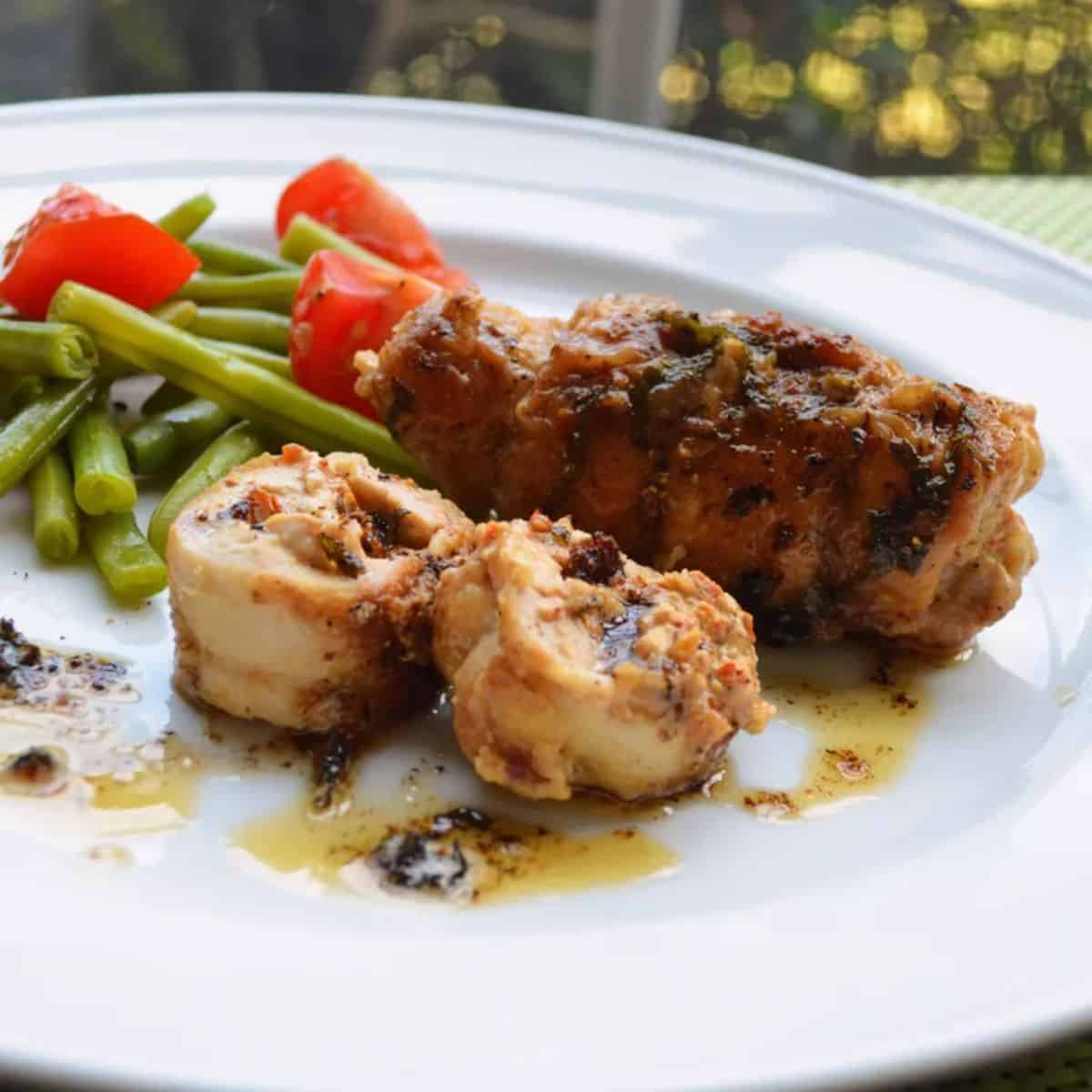 Goat Cheese and Sun-dried Tomato Stuff Chicken Thighs with Sage Brown Butter Sauce on a white plate.