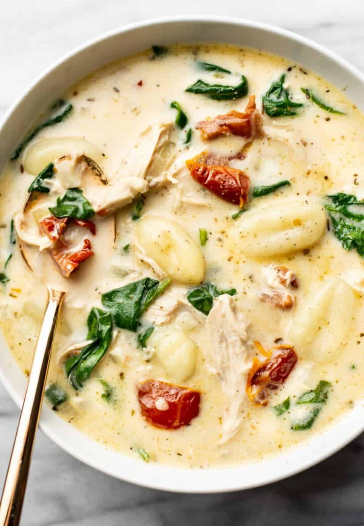 Delicious Creamy Tuscan Chicken Gnocchi Soup in a white bowl.