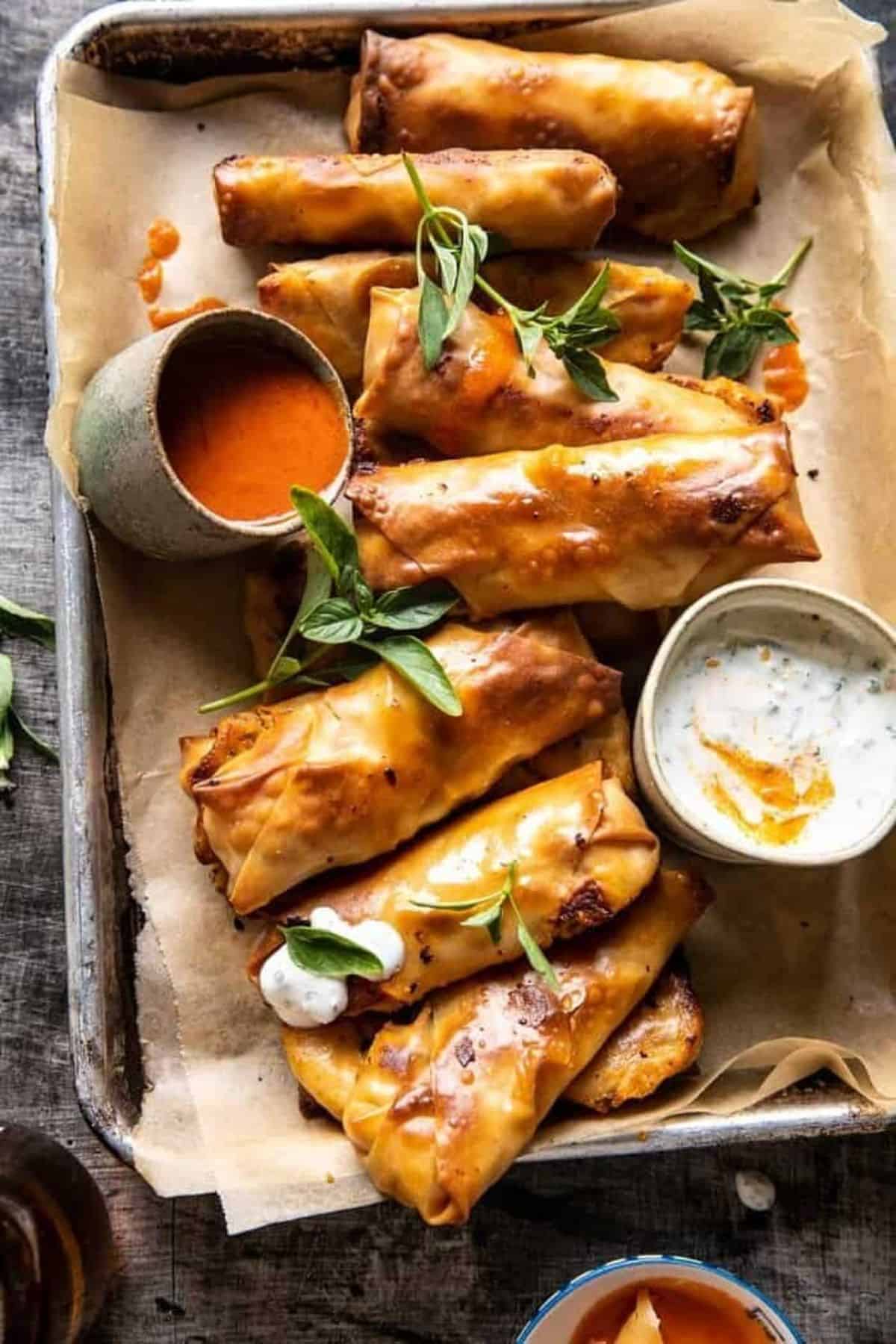 Baked Buffalo Chicken Egg Rolls with Cilantro Lime Ranch in a tray.
