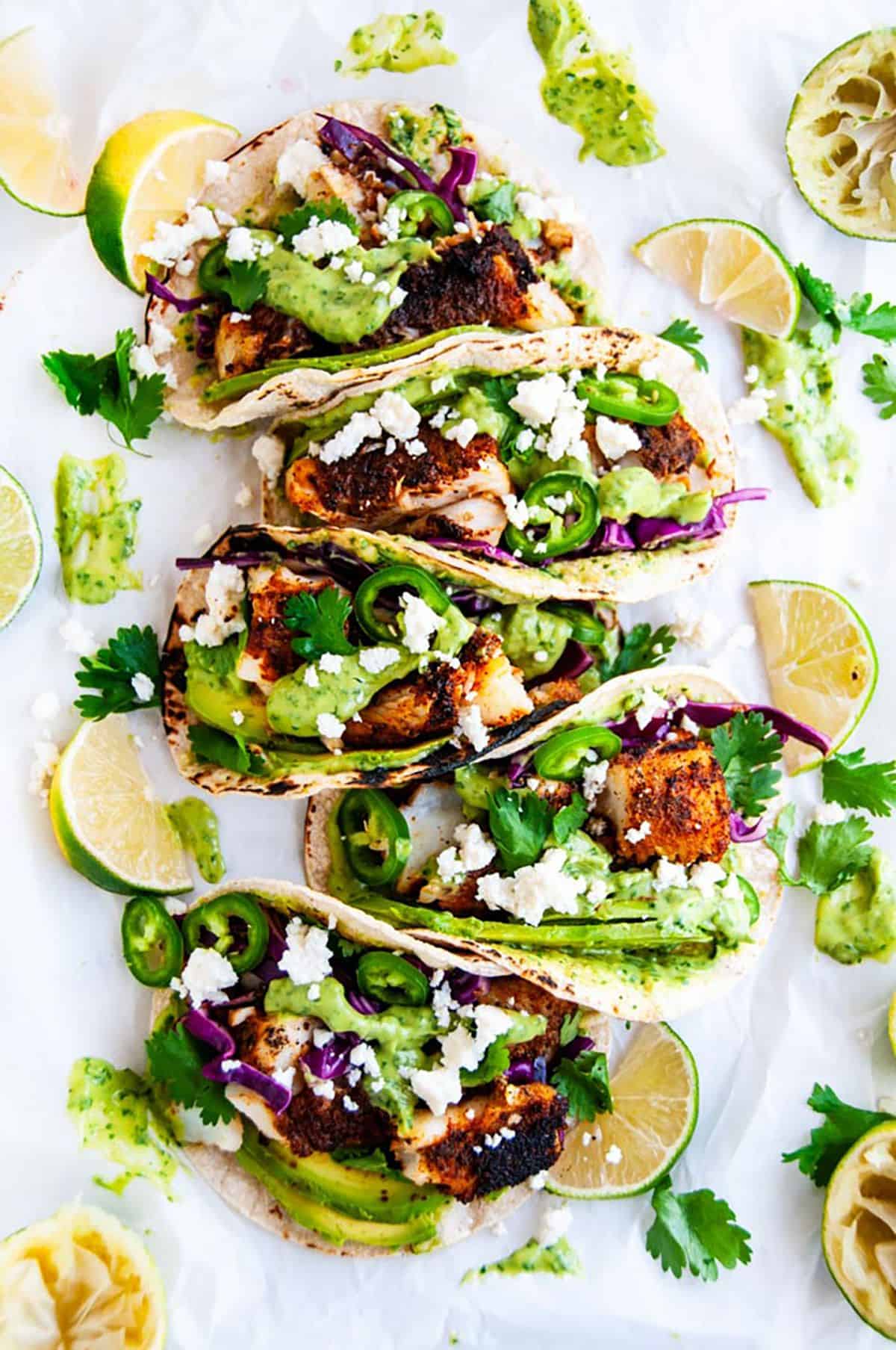 Blackened Cod Fish Tacos with Cilantro Avocado Sauce on parchment paper.