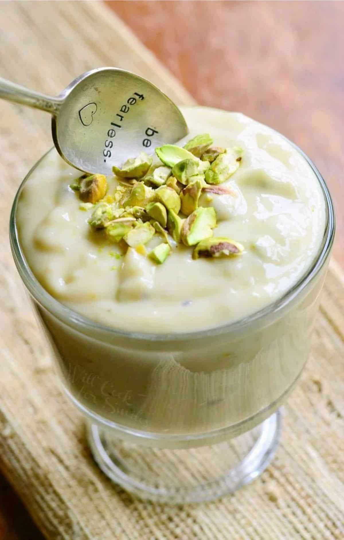 Pistachio Pudding in a tall glass picked with a spoon.