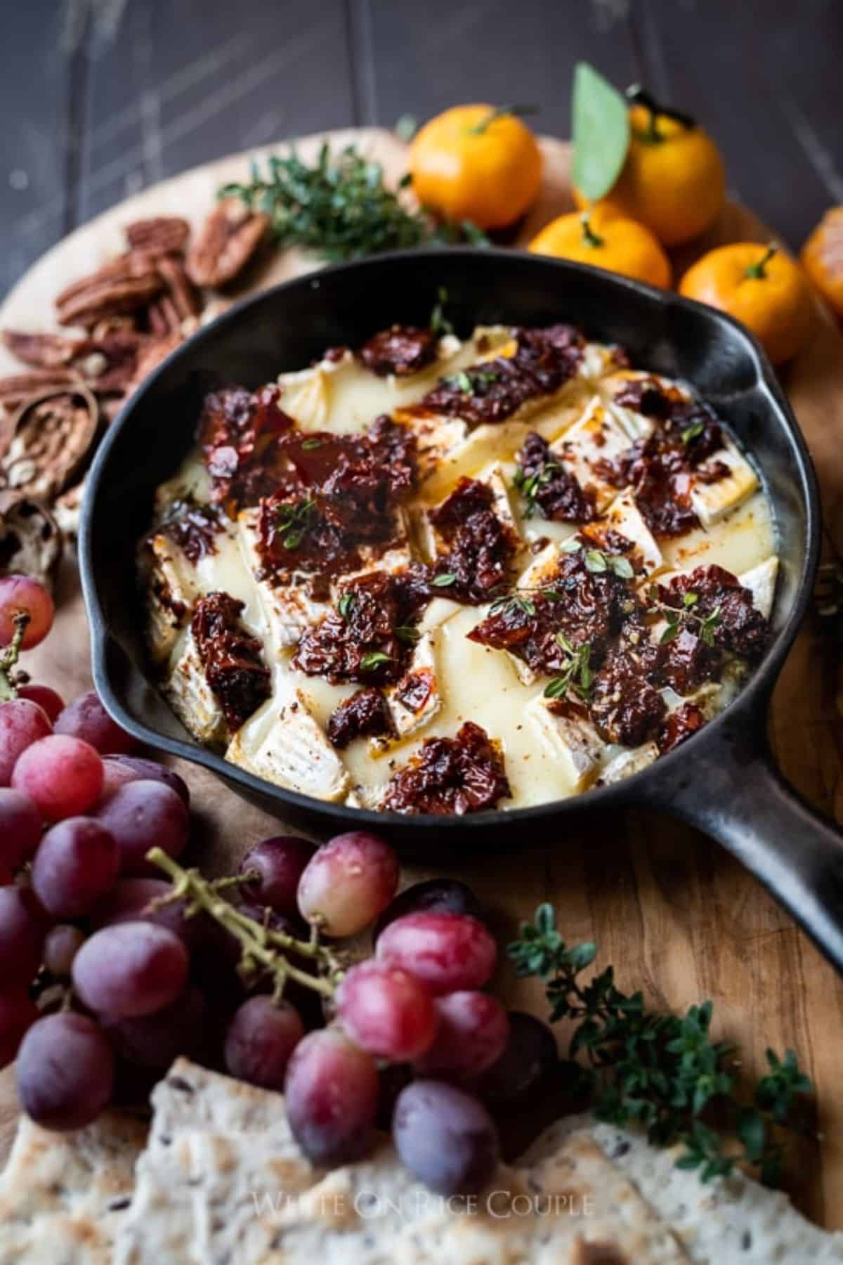 Delicious Baked Brie with Sun-dried Tomatoes in a black skillet.