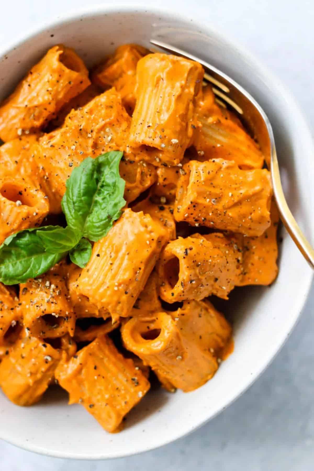 Roasted Red Pepper Cashew Cream Pasta in a white bowl with a fork.